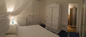 A bedroom with a bed, a wardrobe, and a bathroom with a shower.