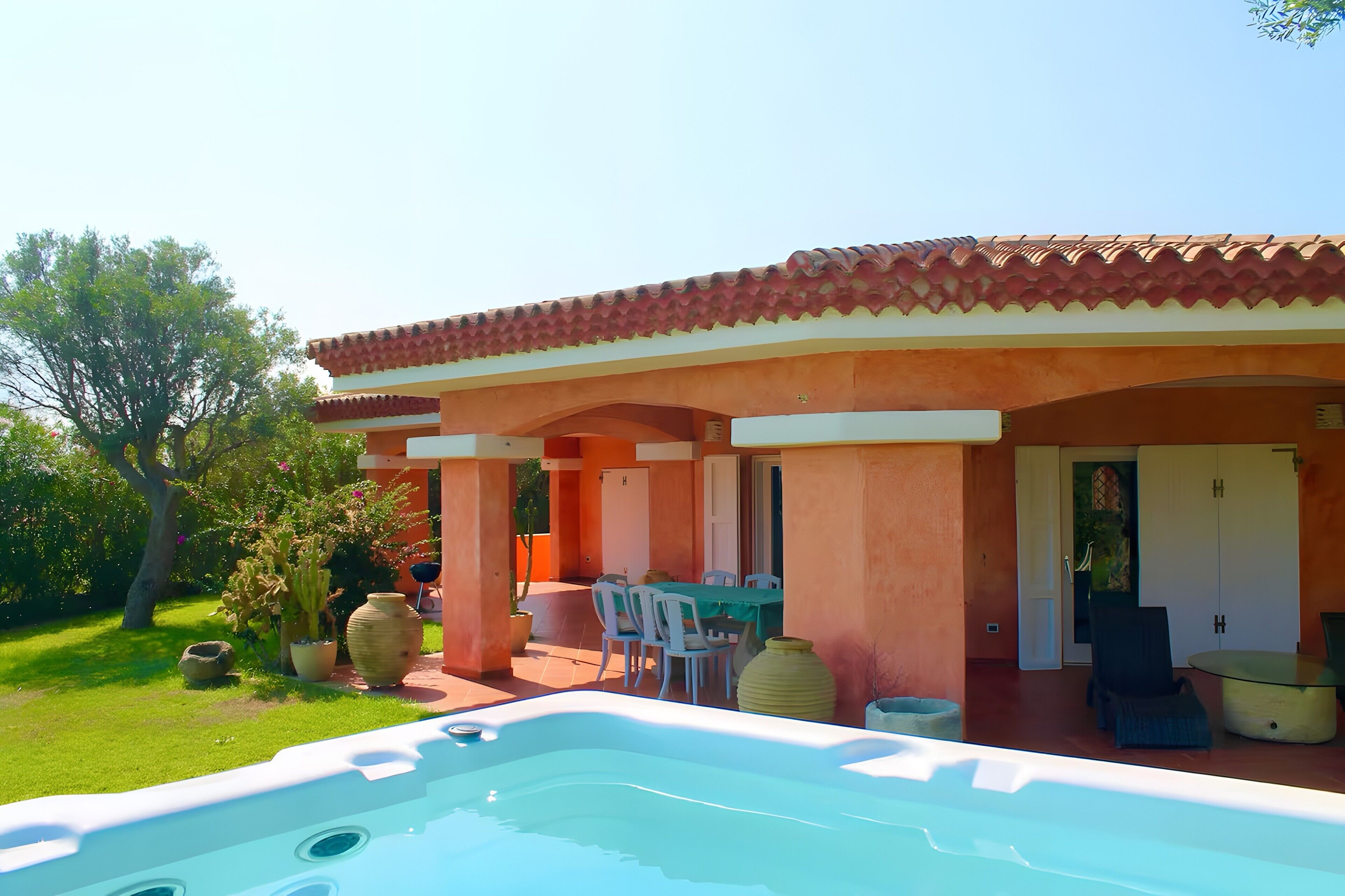 A pool area with a hot tub, outdoor seating, and a covered patio.