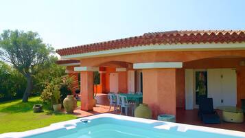 A pool area with a hot tub, outdoor seating, and a covered patio.