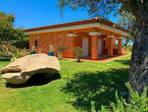A house with a tiled roof, a covered porch, and a well-maintained lawn.