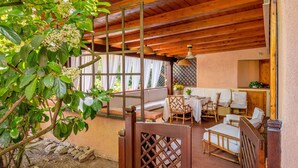 A wooden ceiling, a dining area with tables and chairs, and a garden with a tree. - "Casa Vacanze Miky Punta Asfodeli" Apartment with Terrace, Garden & A/C (Portorotondo)