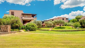 A modern building with a stone facade, surrounded by well-maintained lawns and trees. - "Casa Vacanze Miky Punta Asfodeli" Apartment with Terrace, Garden & A/C (Portorotondo)