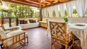 A covered outdoor seating area with wicker furniture, a dining table set for two, and a ceiling fan. - "Casa Vacanze Miky Punta Asfodeli" Apartment with Terrace, Garden & A/C (Portorotondo)