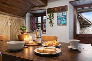 A wooden dining table with plates of bread, croissants, and a coffee pot.