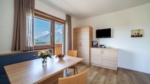 A modern room with a dining table, chairs, a TV, and a view of mountains. - Apartment "Gartenheim Leonhard" with Mountain View, Shared Pool & Wi-Fi (Scena)