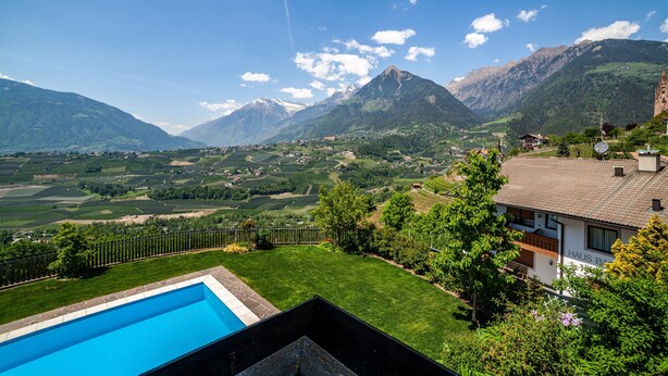 A residential area with a swimming pool, a house with 'HALS B' on the roof, and mountains in the background. - Apartment "Gartenheim Franz" with Mountain View, Shared Pool & Wi-Fi (Scena)