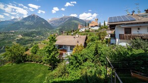 A hillside village with traditional buildings, a prominent church, and a mountain backdrop. - Apartment "Gartenheim Franz" with Mountain View, Shared Pool & Wi-Fi (Scena)