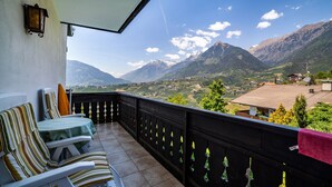 A balcony with a view of mountains, a table with chairs, and a hanging plant. - Apartment "Gartenheim Franz" with Mountain View, Shared Pool & Wi-Fi (Scena)