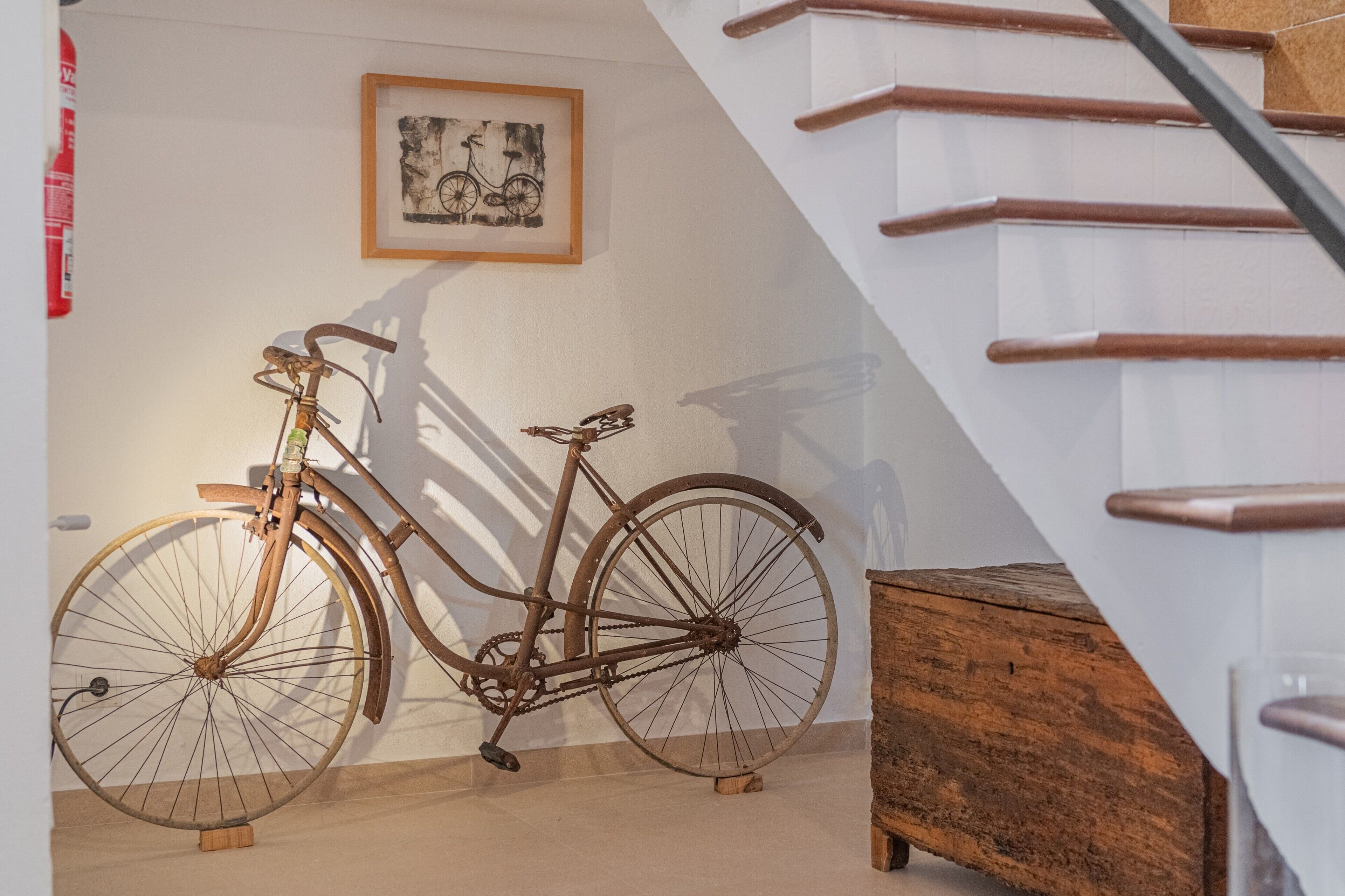 A staircase with wooden handrails, a wooden bench, and a bicycle leaning against a wall.