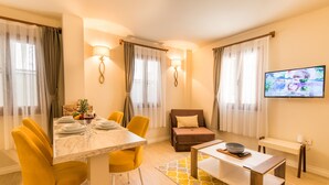 A modern dining area with a marble table, yellow chairs, and a television mounted on the wall.