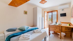 Une chambre à coucher avec un lit, un bureau en bois, une fenêtre et un téléviseur fixé au mur.