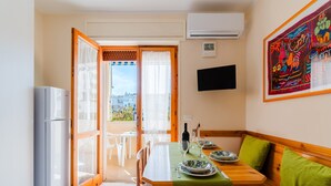 Un coin repas avec une table dressée pour deux personnes, un réfrigérateur et un téléviseur fixé au mur.
