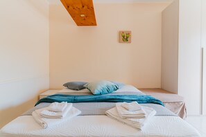 Un lit simple avec des oreillers, une couverture et des serviettes pliées.