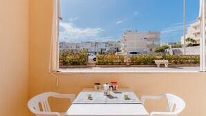 Un balcon avec une table et des chaises, donnant sur des immeubles et une rue.