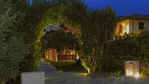 A pathway leading to a building with a stone wall and a wooden fence.