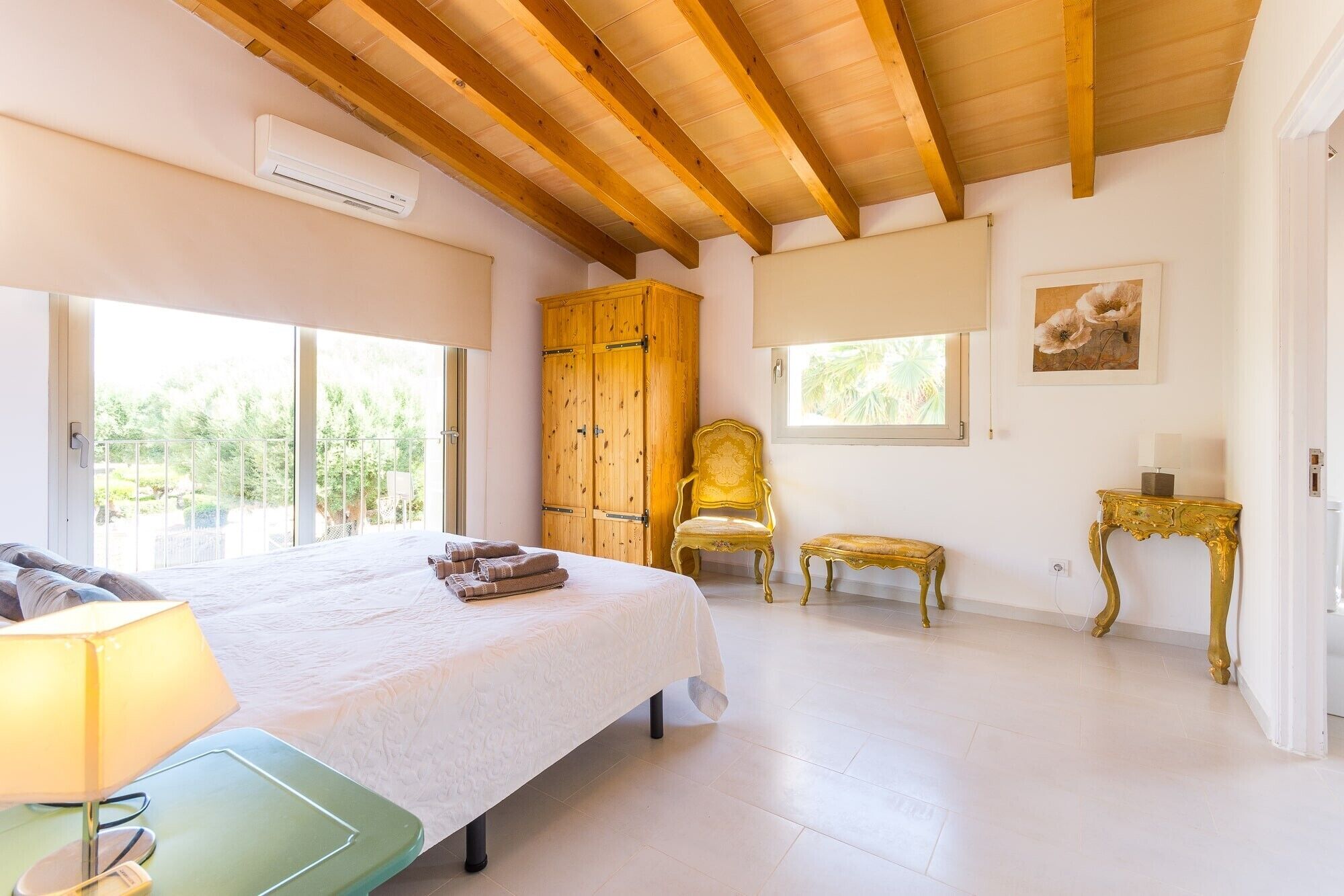 A bedroom with a bed, a chair, a small table, and a wardrobe.