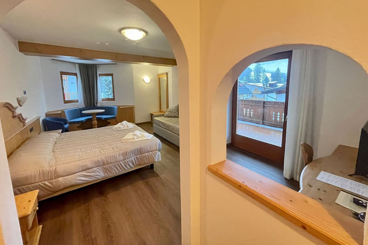 Ein Hotelzimmer mit Bett, Schreibtisch, Stuhl und einem Balkon mit Blick ins Freie.