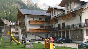 Una zona residencial con un parque infantil, un tobogán amarillo y un edificio con balcones.