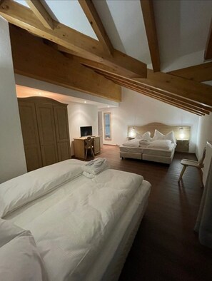 A bedroom with a large bed, a smaller bed, a desk with a chair, and a wardrobe.