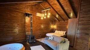 A cozy log cabin interior with a wooden ceiling, a sofa, a white rug, and a hot tub. - Glamping Büyükada (Adalar)
