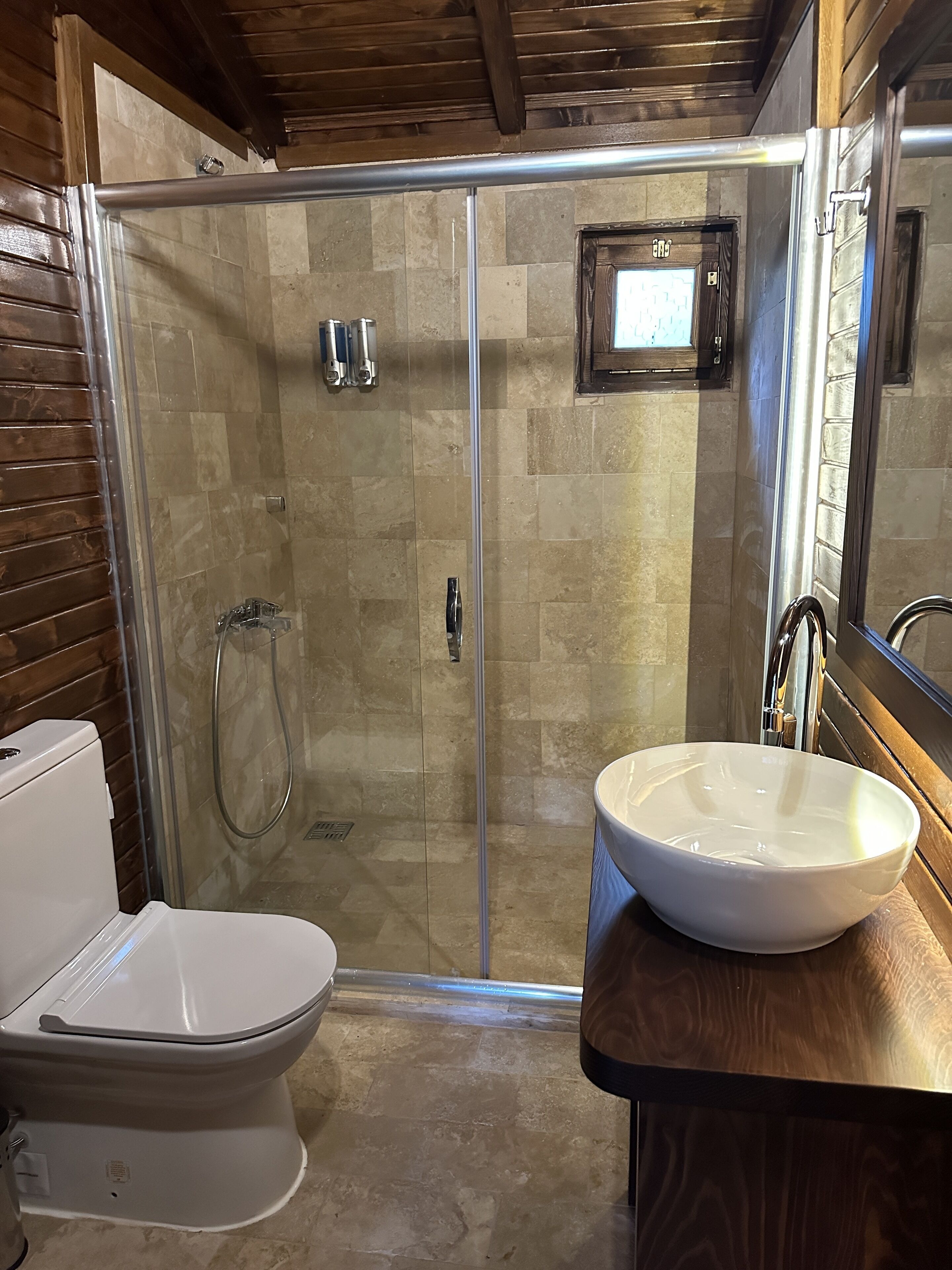 A bathroom with a glass-enclosed shower, a white toilet, and a large white sink.