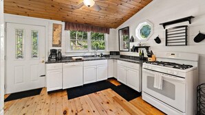 Une cuisine avec des armoires blanches, un comptoir noir, une cuisinière et un ventilateur de plafond.