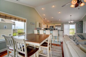 A spacious kitchen with white cabinets, a wooden dining table, and a view of the outdoors.