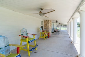 A covered porch with colorful Adirondack chairs and a stone pillar.
