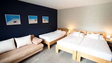 A hotel room with a bed, a sofa, and three paintings on the wall.