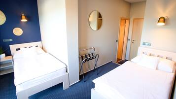 A hotel room with two beds, a mirror, and a wall-mounted light fixture.