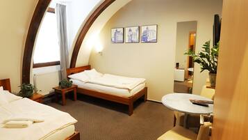 A hotel room with a bed, a small table, a chair, a potted plant, and a mirror.