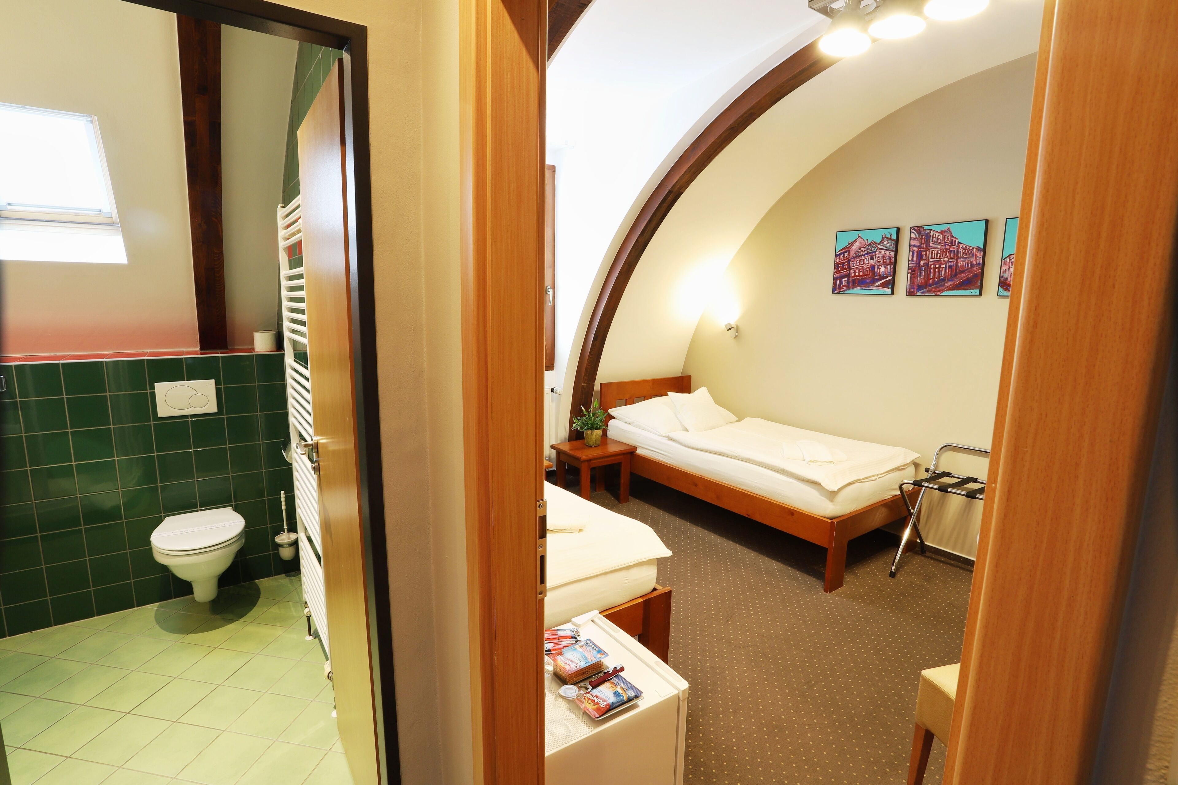 Een hotelkamer met een bed, nachtkastje en een klein raam.