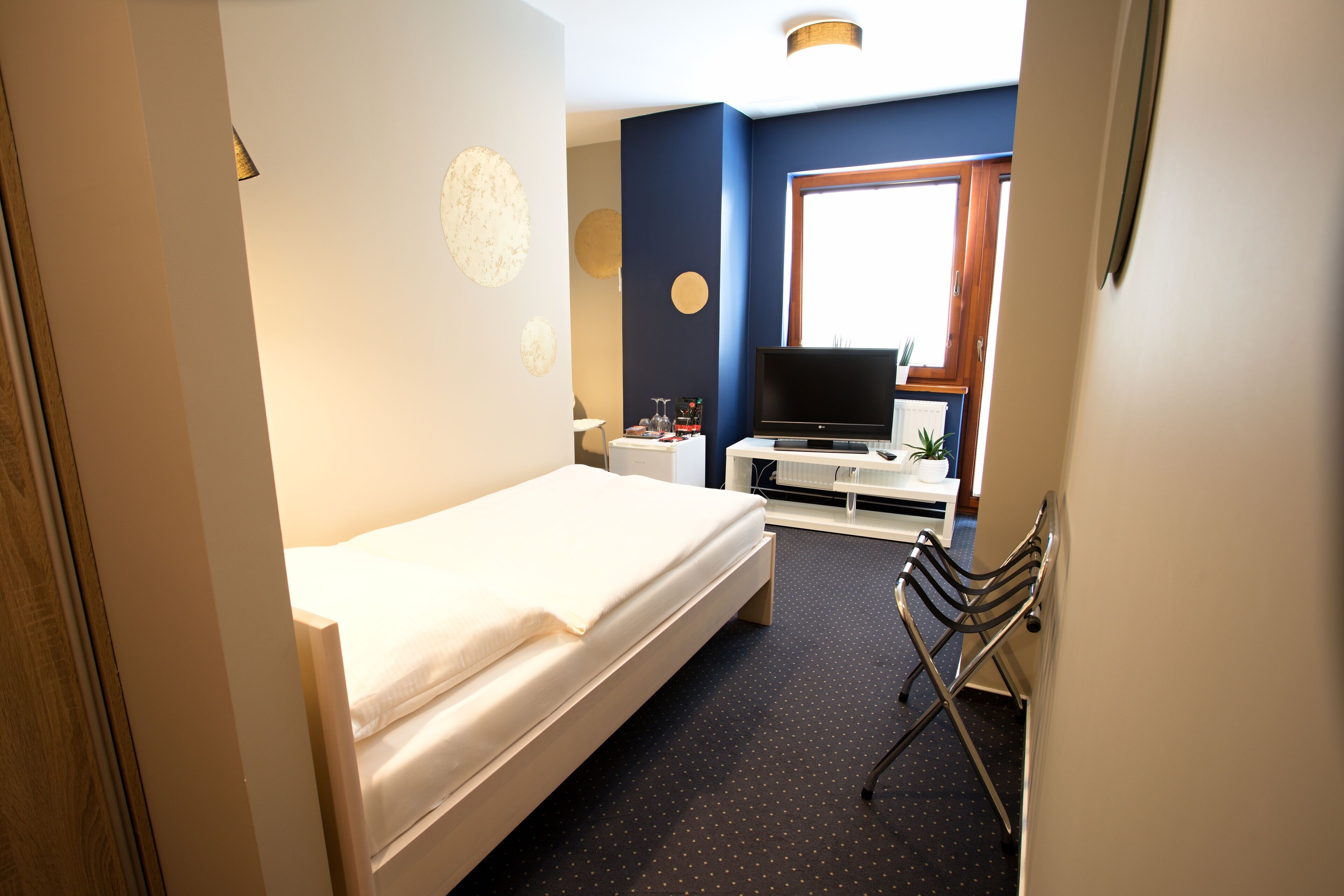Une chambre d’hôtel avec un lit, un bureau avec un ordinateur, une télévision et une chaise.
