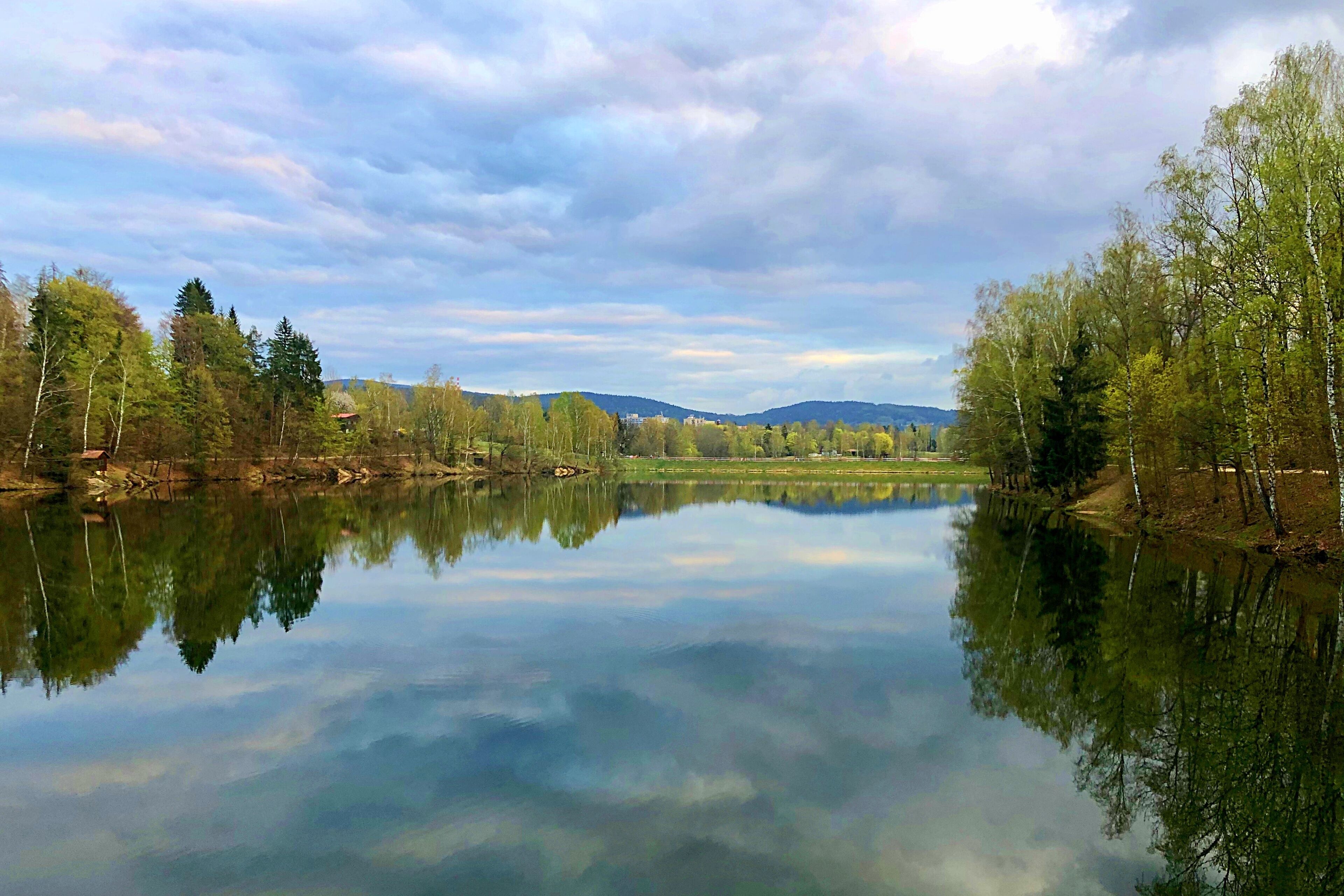A calm lake with reflections of trees and a clear sky.