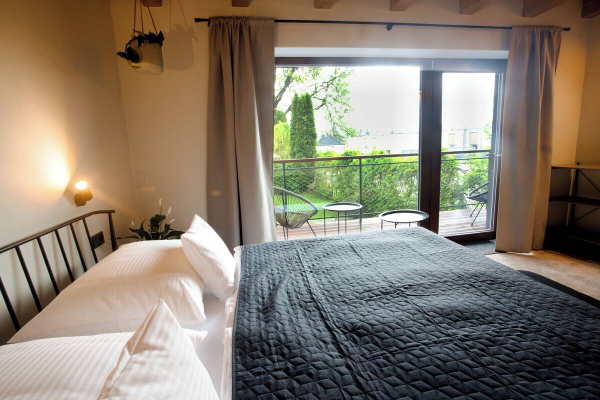 Camera da letto con un letto, un comodino, una pianta in vaso e vista su un balcone con mobili da esterno.