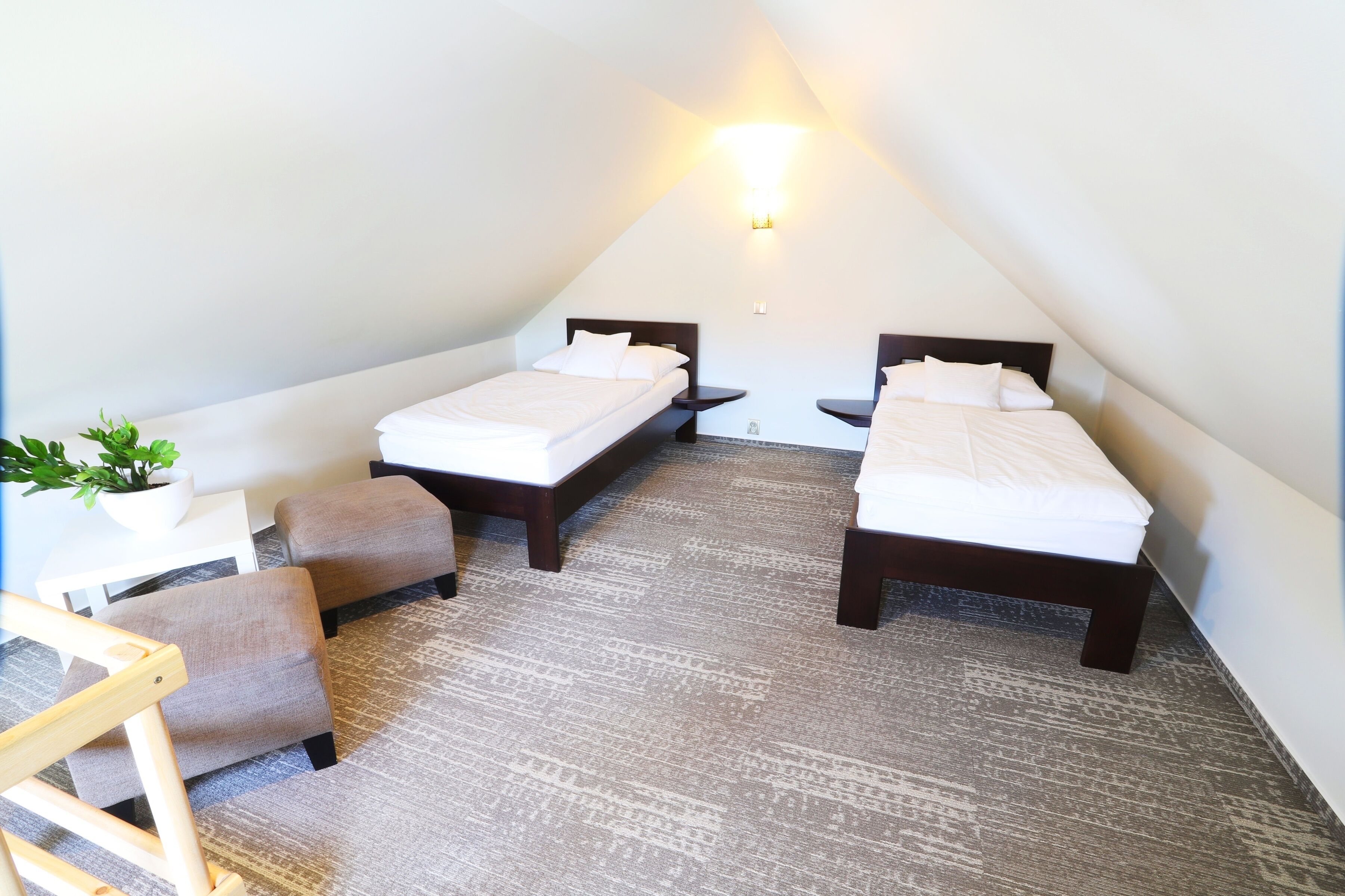 Een kleine, driekantige kamer met twee bedden, een tafeltje en een stoel.
