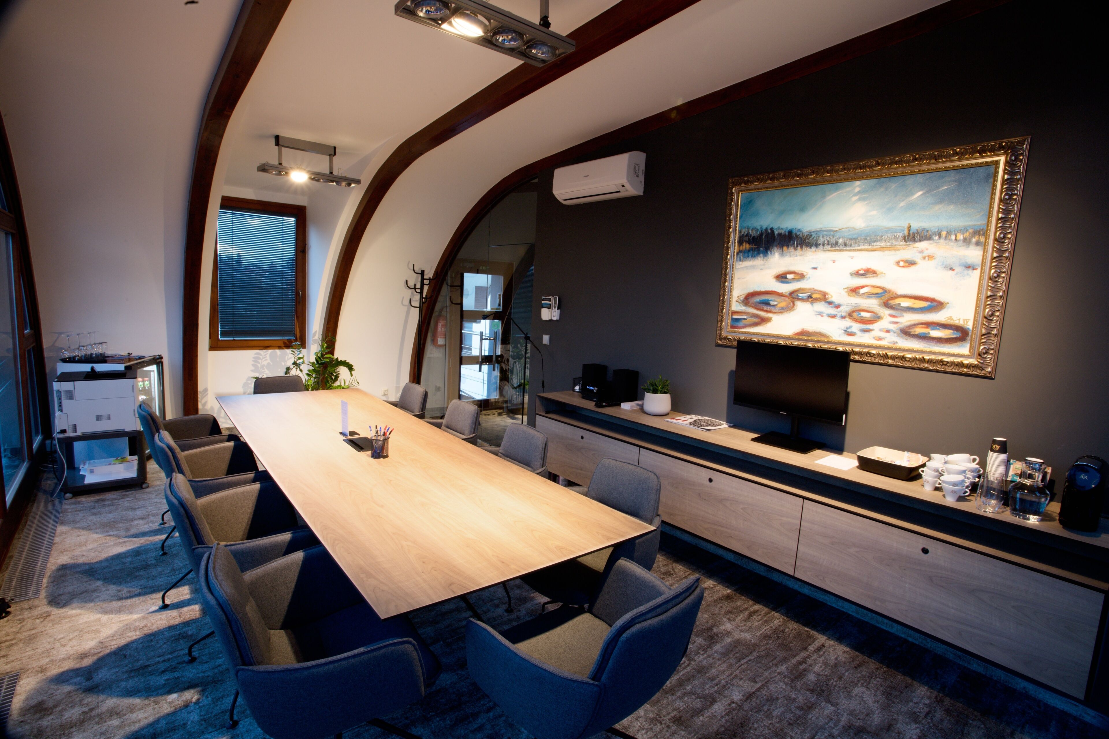 Une salle de conférence équipée d’une longue table, de chaises, d’un tableau et d ’un coin cuisine.