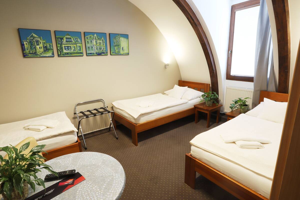 Una camera d'albergo con due letti, un tavolino, una sedia e una finestra con tende.