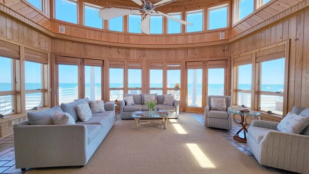A spacious room with a high ceiling, large windows, and a view of the ocean. - Boat House- Oceanfront Hot Tub! Creekfront, Dock & Pool (Pawleys Island)