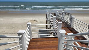 A wooden boardwalk leading to a beach with white railings and a metal gate. - Boat House- Oceanfront Hot Tub! Creekfront, Dock & Pool (Pawleys Island)