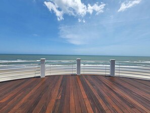 Une terrasse en bois avec une rambarde donnant sur l’océan.