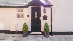 Une maison avec une porte noire, une petite fenêtre et un mur extérieur blanc.