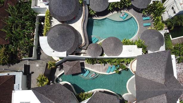 Vist aeri d'un complex turístic amb diverses piscines, zones d'estar i zones d'asseients a l'ombra.