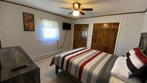 A bedroom with a bed, a desk, a ceiling fan, a TV, and a window with curtains. - Hidden gem, 2BR-2 Living, quiet neighborhood (Plattsburgh)