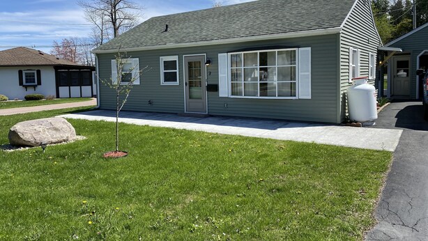 A single-story house with a front porch, a small tree, and a large rock in the yard. - Hidden gem, 2BR-2 Living, quiet neighborhood (Plattsburgh)