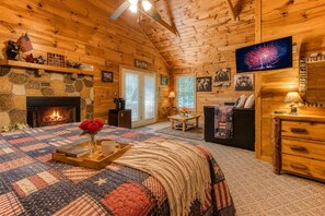 A cozy log cabin interior with a fireplace, a television, and a comfortable seating area.