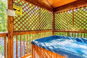 A hot tub in a wooden gazebo with a lattice roof and a caution sign about squirrels.