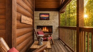 A log cabin with a stone fireplace, wooden deck, and a sign that reads 'Sit Long Talk Much.' - American Spirit, Free Tickets, Hot Tub, WIFI, “Cozy Cabin Retreat in the Smokies (Sevierville)
