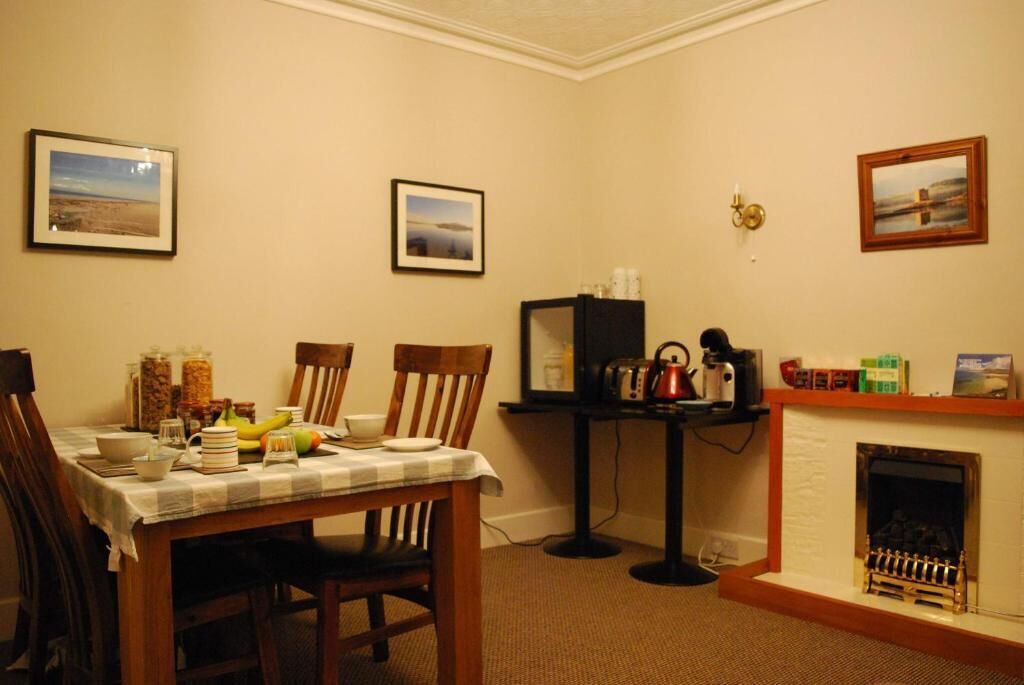 A dining area with a table set for four, a fireplace, and framed pictures on the walls.