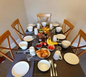 Mesa de jantar posta com pratos, tigelas, talheres e diversos alimentos.